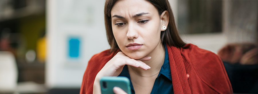 woman looking at her phone with a concerned look on her face