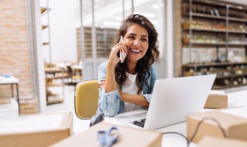 woman talking on the phone while sitting in front of a laptop