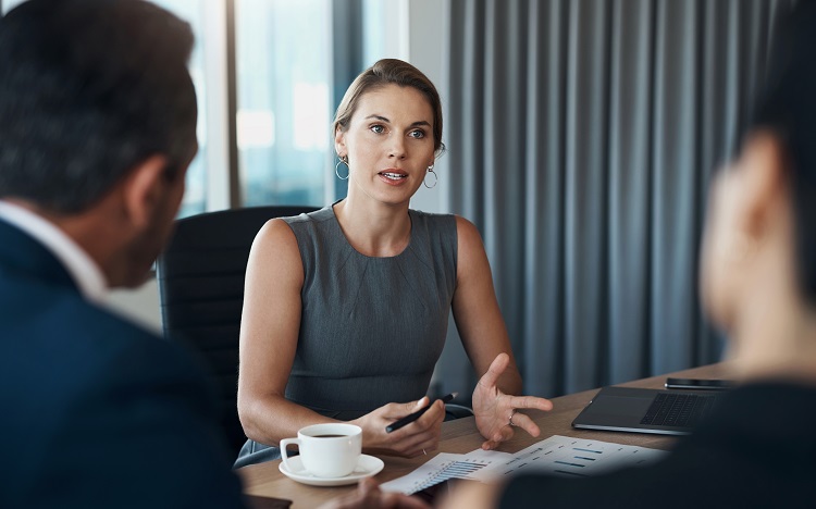 Woman in a meeting speaking to non-facing colleagues.