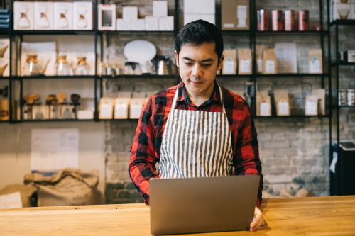 man working on laptop behind a counter