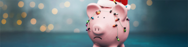 a sad-faced piggy bank wearing a santa hat and festive lights