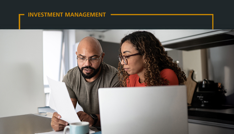 couple sitting at a table with a laptop and reviewing documents together